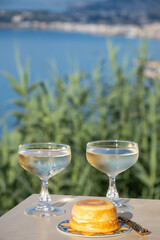 Sweet italian dessert ricotta cheese baked with lemon and glasses of Prosecco sparkling wine served on Ligurian coast with view on sea, summer in Italy
