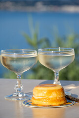 Sweet italian dessert ricotta cheese baked with lemon and glasses of Prosecco sparkling wine served on Ligurian coast with view on sea, summer in Italy