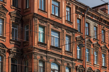 Side view of traditional ornate tawny coloured facade with group of windows on wall of residential building in Saint Petersburg, Russia. Copy space. Architecture and city street background theme.