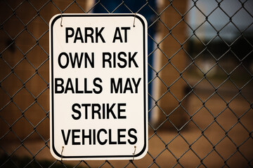 "Park at Own Risk" sign stating that foul balls may strike vehicles in the area.