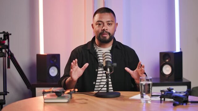 Interview, microphone and podcast presenter with man in recording studio for broadcast or live stream. Creative, media and radio with portrait of influencer speaking on air as talk show presenter