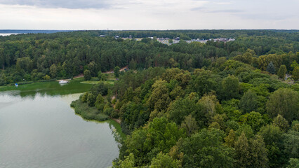 Drone photography of a town and music festival in background surrounded by forest during summer day