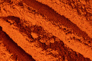 Abstract terracotta striped background of scattered paprika seasoning
