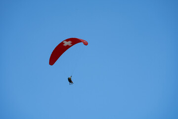 Tandem paragliders against a blue sky near Murren Switzerland in the Bernese Oberland, parachute with the Swiss flag