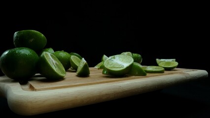 Close-up, a vibrant slice of fresh lime rests upon a rustic wooden cutting board, exuding freshness and vitality. The translucent membranes of the green lime slice placed on cutting board. Comestible.