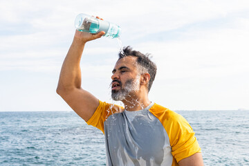 Indian man cooling off with water on a summer day by the sea