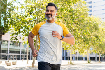Indian man running in summer wearing a smartwatch