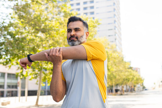 Indian man stretching outdoors during summer workout