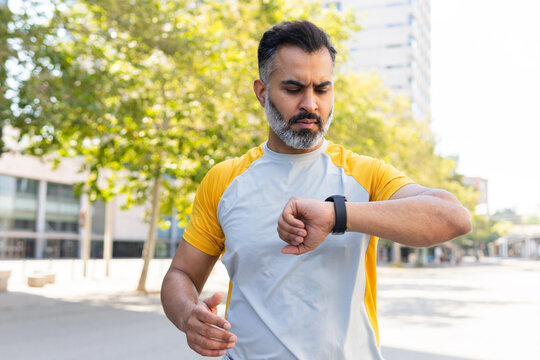 Indian man checking time on smartwatch during summer jog
