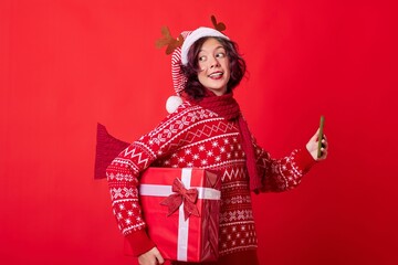 An image of a young woman wearing a Santa hat with reindeer antlers and a red and white striped...
