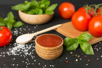 Delicious ketchup with spices and tomatoes on wooden table