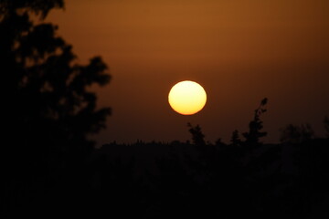 Epic sunset landscape sky with big bright sun going behind the mountains in Greece