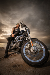 Rocker Posing with Chopper Motorcycle at Sunset