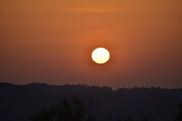 Epic sunset landscape sky with big bright sun going behind the mountains in Greece