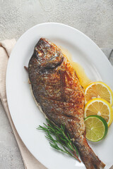 baked dorado fish, in the oven, fried dorado, with spices and herbs, on a white plate, top view, homemade, no people,