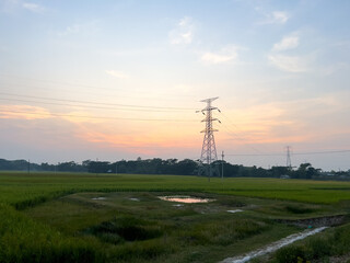 High-Voltage Power Lines Across Rural Farmland in Bangladesh Under Clear Blue Sky. Electric Pylon. power lines