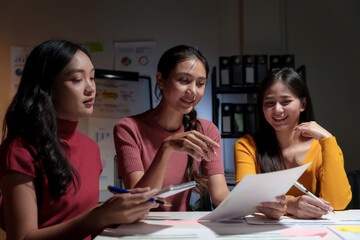 Three asian businesswomen working together using laptop computer and financial document, they are discussing about their project