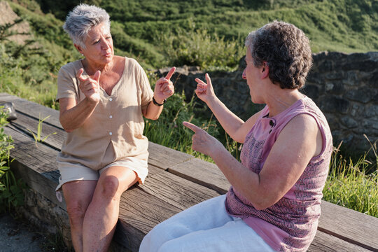 Senior deaf women communicating through sign language outdoors