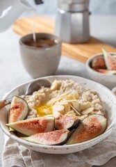 A wholesome bowl of oatmeal topped with fresh figs and sliced almonds, set on a rustic linen cloth. Accompanying small bowls of figs and almonds enhance the cozy breakfast scene