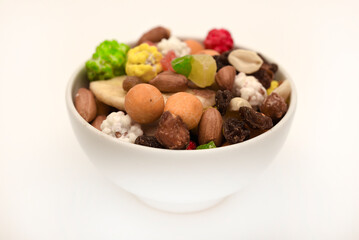Sweet assorted nuts and dried fruits in a plate on a white background.