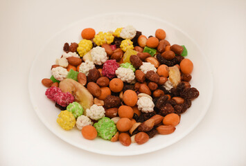 Sweet assorted nuts and dried fruits in a plate on a white background.