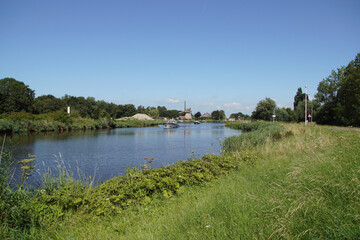 Dutch landscape with a canal (Noordhollandsch Kanaal), windmill (De Sluismolen, 1575), boats, float bridge. Village of Koedijk. Summer, July, Netherlands