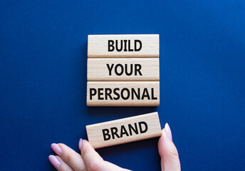 Build your personal Brand symbol. Concept words Build your personal Brand on wooden blocks. Businessman hand. Beautiful deep blue background. Business and Build your personal Brand concept. Copy space