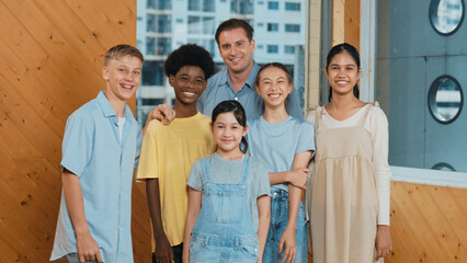 Happy teacher and diverse student standing while smilling to camera. Professional smart instructor with highschool children with mixed races in casual outfit pose at camera with cheerful. Edification.