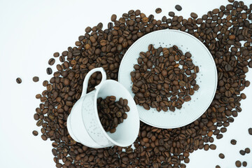 coffee scattered on a saucer and inside a beautifully decorated cup surrounded by a large amount of coffee beans. Feel power in the morning and enjoy your espresso. White background add your content