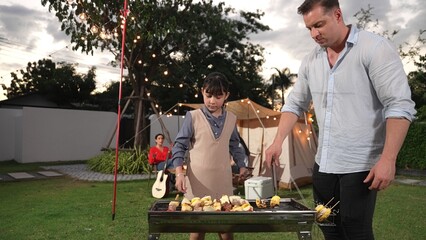 Family together camp in garden, father and child grill food for family member. Outdoor camping...