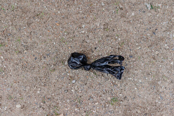Black small package on the ground. Dog excrement in a bag.