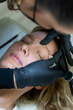 Beautician performing microblading treatment on client