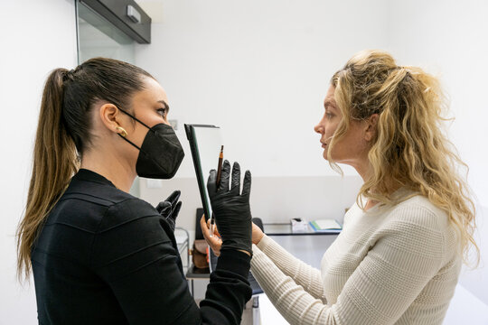 Beautician explaining microblading procedure to a client