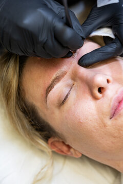 Beautician performing microblading on woman's eyebrows