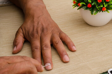 A person is using a cuticle remover file to clean their nails