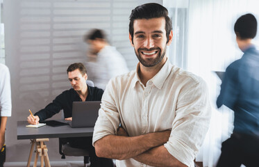 Confidence and happy smiling businessman portrait with blur motion background of his colleague and business team working in office. Office worker teamwork and positive workplace concept. Prudent