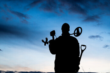 silhouette of a person with a metal detector