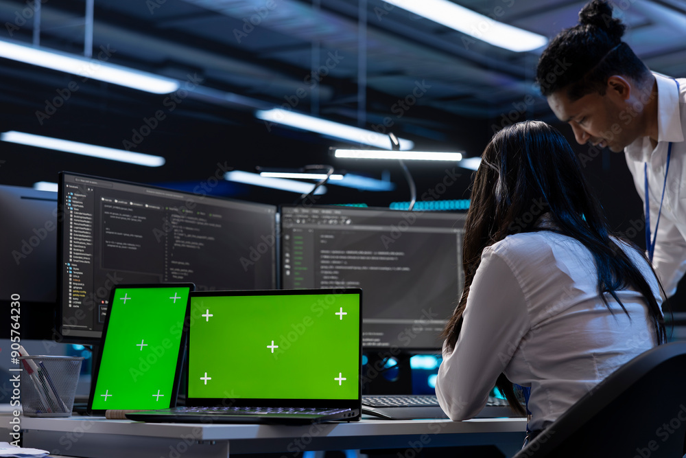 Poster engineers in data center using isolated screen laptop and tablet to find firewall misconfigurations 