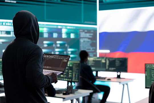 Dishonest person in a Russian cyber security room hacking systems, spreading misinformation and fake news. Russian hackers group on hybrid war tactics and international conflict. - Powered by Adobe