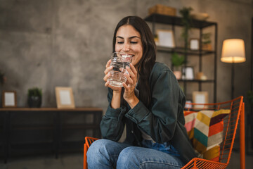 Portrait of adult young women sit in a chair and hold glass of water