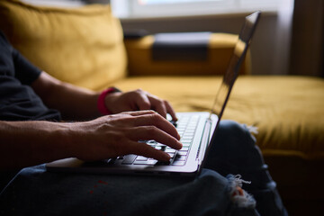 Obraz premium A person is happily typing on a laptop while sitting comfortably in a cozy living room setting