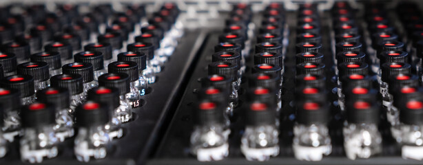 Obraz premium HPLC glass vials with black caps in the auto sampler are waiting for injection. 