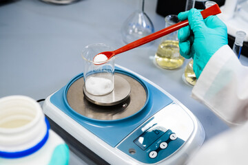 Close up of a woman weighing powder samples using laboratory balances