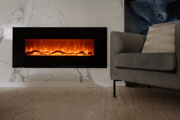 Living room with electric fireplace and chair against marble wall