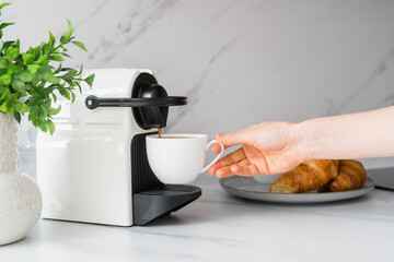 Woman makes her morning coffe using espresso machine at home