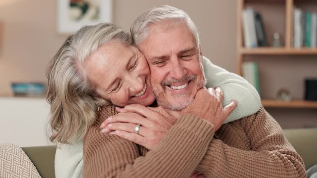 Senior couple, hug and kiss with care for relationship, retirement and marriage commitment in home. Happy, elderly man and woman with embrace on sofa for love bonding, support and loyalty with trust