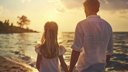 Fototapeta premium Caucasian man and child holding hands on beach at sunset
