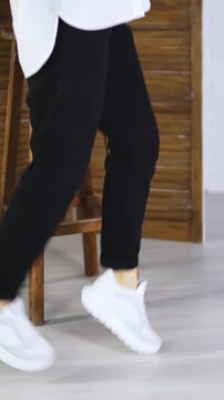 Model jumping high to show white spot shoes. Demonstrating comfortable footwear for everyday activity. Folding screen and tabouret at backdrop. Vertical video
