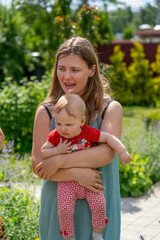 A woman joyfully holds her baby while enjoying a sunny day outdoors