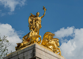 New York, NY, USA - August 2, 2023:  Maine monument golden statue top closeup on SW corner Central Park under blue cloudscape
